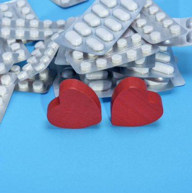 bir paket ve iki kırmızı kalp mavi bir arka plan kopya alanı üzerinde farklı hapları yığını