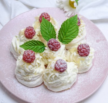 pişmiş kek yumurta beyazı yaptı ve pembe tabağa Pavlova tatlı ahududu ile beyaz krem şanti