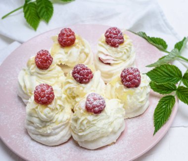 pişmiş kek yumurta beyazı yaptı ve pembe tabağa Pavlova tatlı ahududu ile beyaz krem şanti