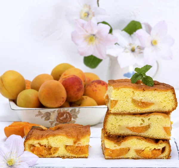 yığın kayısı taze meyve arkasında beyaz bir ahşap tablo ile bisküvi pastası