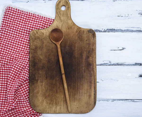 brown old kitchen cutting board and wooden spoon on white table, top view
