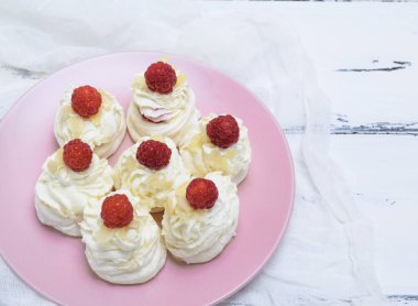 pişmiş kek yumurta beyazı yaptı ve pembe tabağa Pavlova tatlı ahududu ile beyaz krem şanti
