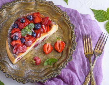 çilek bir demir bakır plaka ve iki çatal, üstten görünüm ile yarım cheesecake