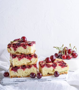 kare adet kiraz bir beyaz ahşap tahta, beyaz arka plan, kopya alanı ile Bisküvi pasta pişmiş