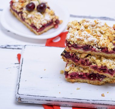 Beyaz ahşap tahta üzerinde kiraz çilek ile bir pasta fırında grafiğin dilimlerini yığını