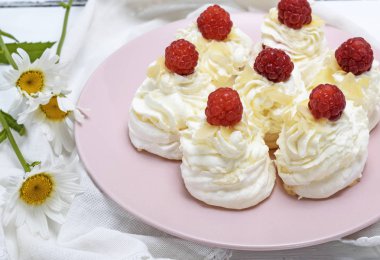 kek beyaz yumurta yaptı ve pembe tabağa Pavlova tatlı ahududu ile beyaz krem şanti