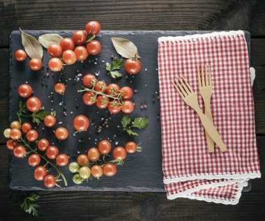 iki ahşap bir kırmızı Tekstil Mutfak havlu ve olgun kırmızı kiraz domates, üstten görünüm üzerinde çatal
