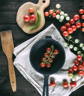 Dökme demir tava ve olgun kırmızı kiraz domates kahverengi ahşap bir masa üstten görünüm üzerinde yuvarlak