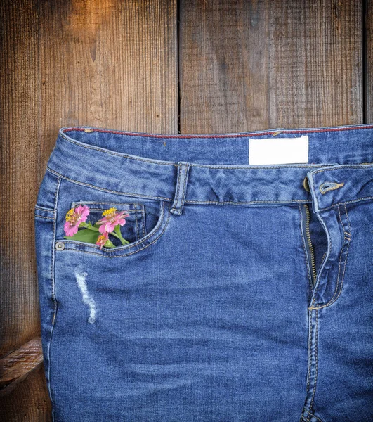 Fragment Blå Jeans Med Bukett Blommor Främre Ficka Brun Trä — Stockfoto