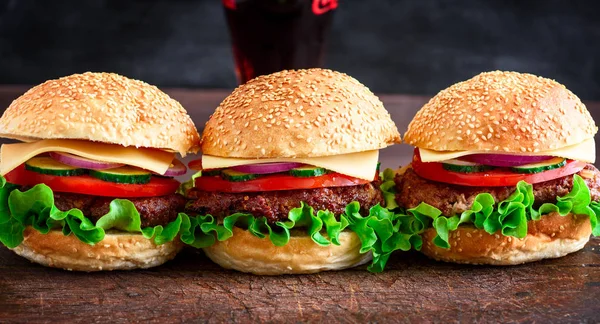 Hamburger with beef, cheese and vegetables on rustic wooden brown cutting board, closeup