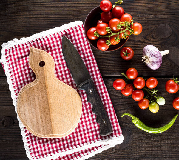 kitchen cutting board and knife, near ripe red cherry tomatoes, top view