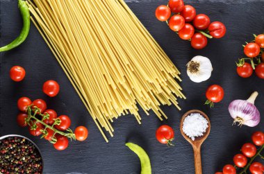 Siyah arka plan, kırmızı domates ve sarımsak sosu, en iyi görünüm için pişmemiş makarna spagetti