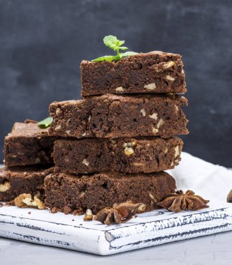 yığın kare parça çikolatalı brownie pasta bir eski kahverengi ahşap kesme tahtası üzerinde ceviz ile pişmiş, yakın çekim