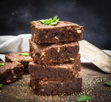 bir eski kahverengi ahşap kesme tahtası, yakın upo üzerinde ceviz ile çikolatalı kek pasta pişmiş kare parçaları yığını