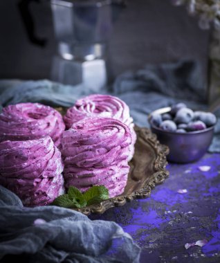 Bakır bir tabakta duran pudra şekeriyle serpilmiş büyük pembe marşmelov.