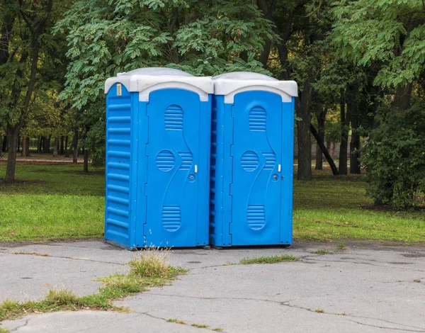 Biotoilete iki mavi kabinleri şehir parkın ortasında bir yaz günü ayağa.