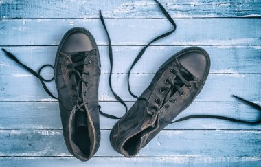 siyah tekstil ayakkabı ile gevşetti dantel yalan üzerine mavi ahşap arka plan, üstten görünüm