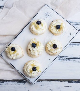Küçük pişmiş yuvarlak pasta beze Beyaz ahşap tahta, üstten görünüm krem şanti ile