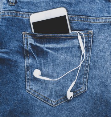 Kot pantolonun arka cebinde kulaklık olan beyaz akıllı telefon.