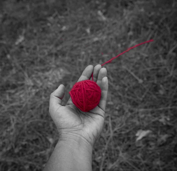 red wool clew in human hand, top view, close up