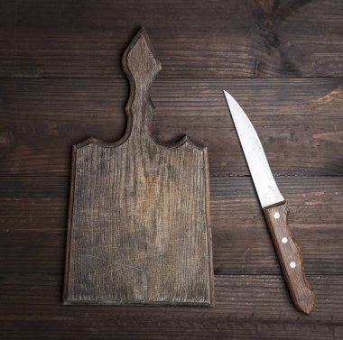 Çok eski, boş bir mutfak kahverengi kesme tahtası, sapı ve bıçağı masanın üstünde.