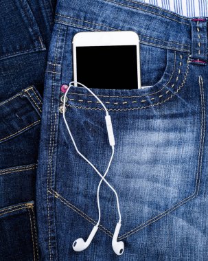a boş siyah perde ve kulaklık ile beyaz akıllı telefon açık mavi kot pantolon cebinde, yakın çekim