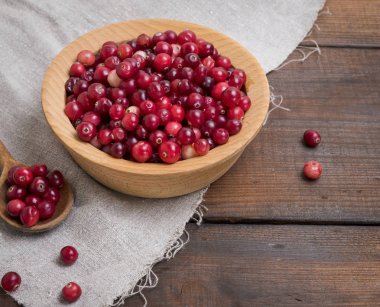 üstten görünüm kahverengi bir masada ahşap bir kasede olgun lingonberries kırmızı meyveler