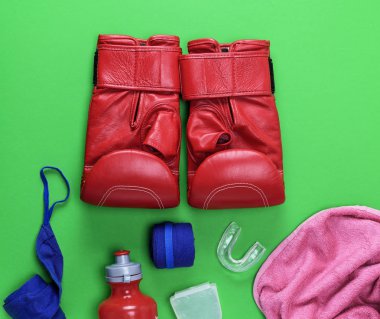 kırmızı deri boks eldiveni, plastik su şişesi ve pembe havlu ve yeşil bir arka plan üzerinde mavi Tekstil bandaj