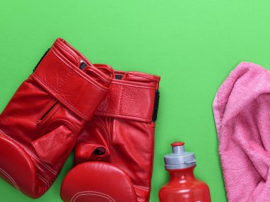 kırmızı deri boks eldiveni, plastik su şişesi ve yeşil bir arka plan boşluk üst üzerinde pembe havlu