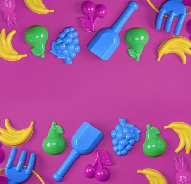 Meyve şeklinde plastik oyuncaklar ve pembe arka planda bir kova, boşluğu kopyala