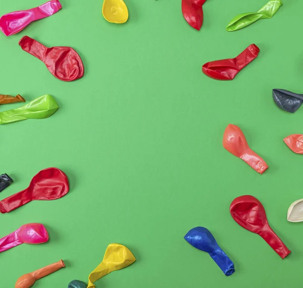 colorful deflated balloons on a green background, copy space