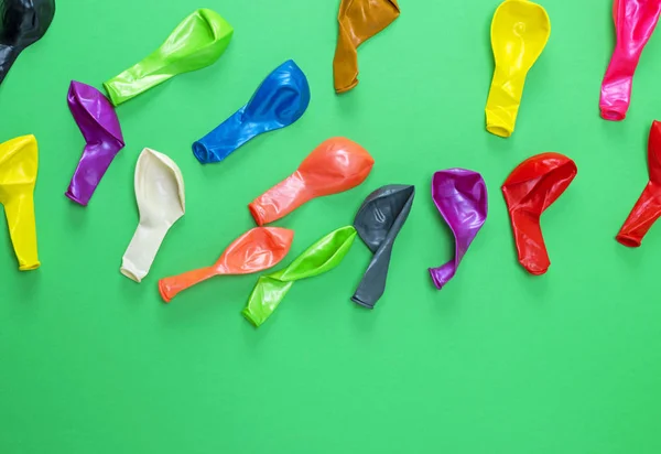 colorful deflated balloons on a green background, copy space