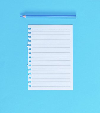 Not defteri ve mavi ahşap kalem mavi zemin üzerine dışarı yırtık doğrultusunda beyaz boş sayfa