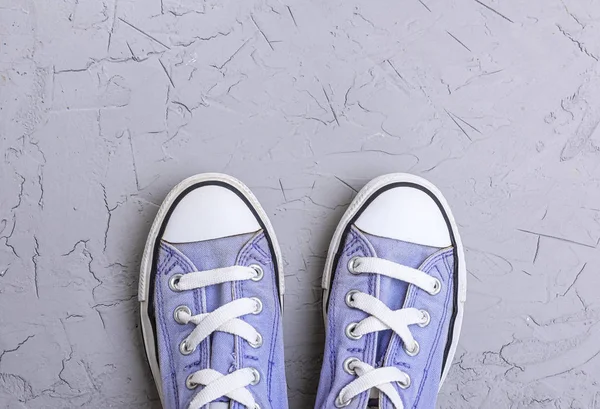 pair of old worn purple  sneakers with white laces on a gray  background, top view