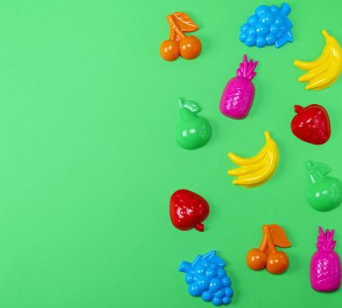 çok renkli plastik oyuncaklar meyve üzerinde yeşil bir arka plan kopya alanı