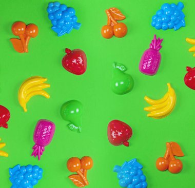 yeşil bir arka plan üzerinde birçok çok renkli plastik oyuncaklar meyve yakın çekim
