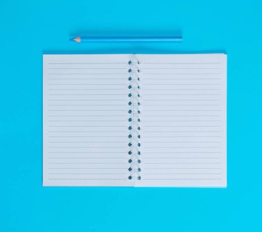 defter ile satır ve mavi ahşap kalem, mavi arka plan, üstten görünüm boş beyaz çarşaf