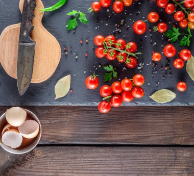 Olgun kırmızı kiraz domates, eski bir bıçak ve tavuk yumurta, bir kabuk ile tahta kesme görünümü top
