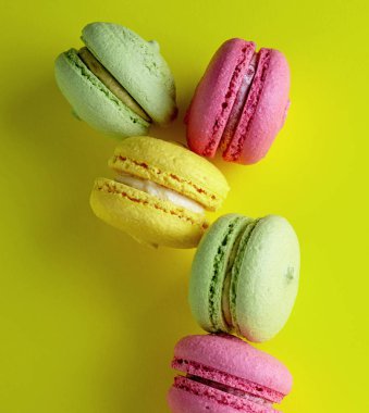 çok renkli yuvarlak badem yemek beze hamur işleri macarons üzerinde parlak sarı bir arka plan, yakın çekim