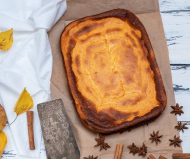 Bütün dikdörtgen kek süzme peynir ve kabak bir masada Beyaz ahşap, metal mutfak spatula yakınındaki üstten görünüm