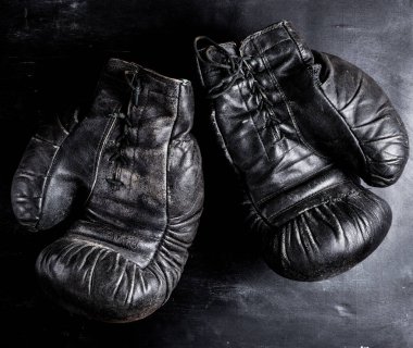 Bir çift eski deri boks eldiveni, ahşap arka planda bağcıklar, klasik tonlama.