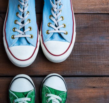 Kahverengi ahşap bir yüzey üzerinde yeşil ve mavi tekstil spor ayakkabıları.