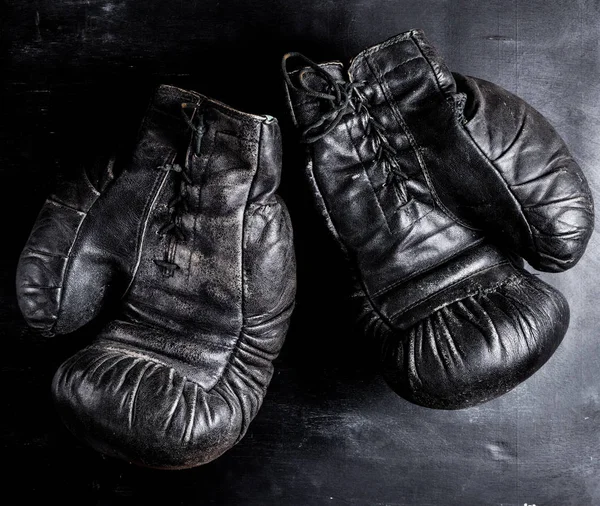 pair of old leather boxing gloves with laces on a wooden background, vintage toning