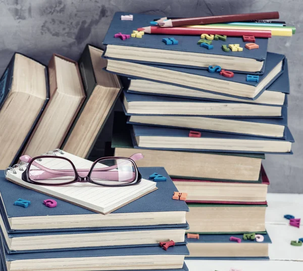 堆叠在蓝色封面的书籍 粉红色的眼镜在上面 — 图库照片