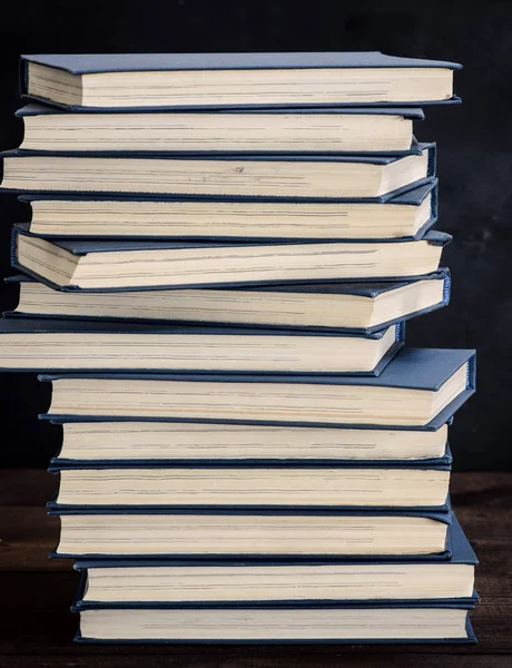 堆栈的书籍在一个蓝色的封面上的棕色木桌 — 图库照片