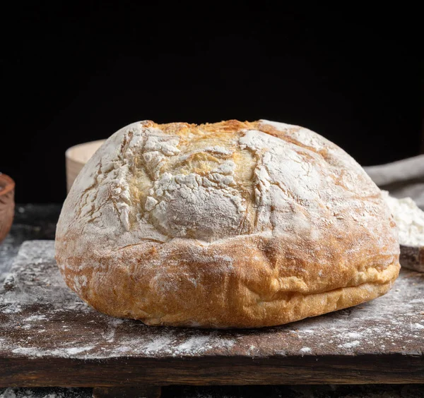 Tahta üzerinde beyaz buğday unundan yapılmış fırınlanmış ekmek, siyah arka plan.