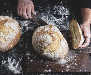 adam pişmiş yuvarlak ekmek keser bir kahverengi ahşap masa, üstten görünüm