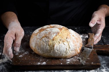 yuvarlak bir eski kahverengi ahşap tahta ve Şef eller ev yapımı ekmek