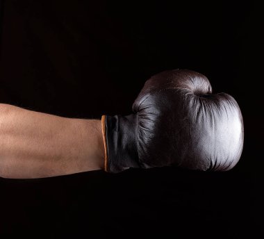 Elini bir kahverengi deri boks eldiveni, siyah arka plan giyiyor