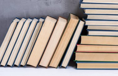 Masada bir yığın kitap var, gri arkaplan.